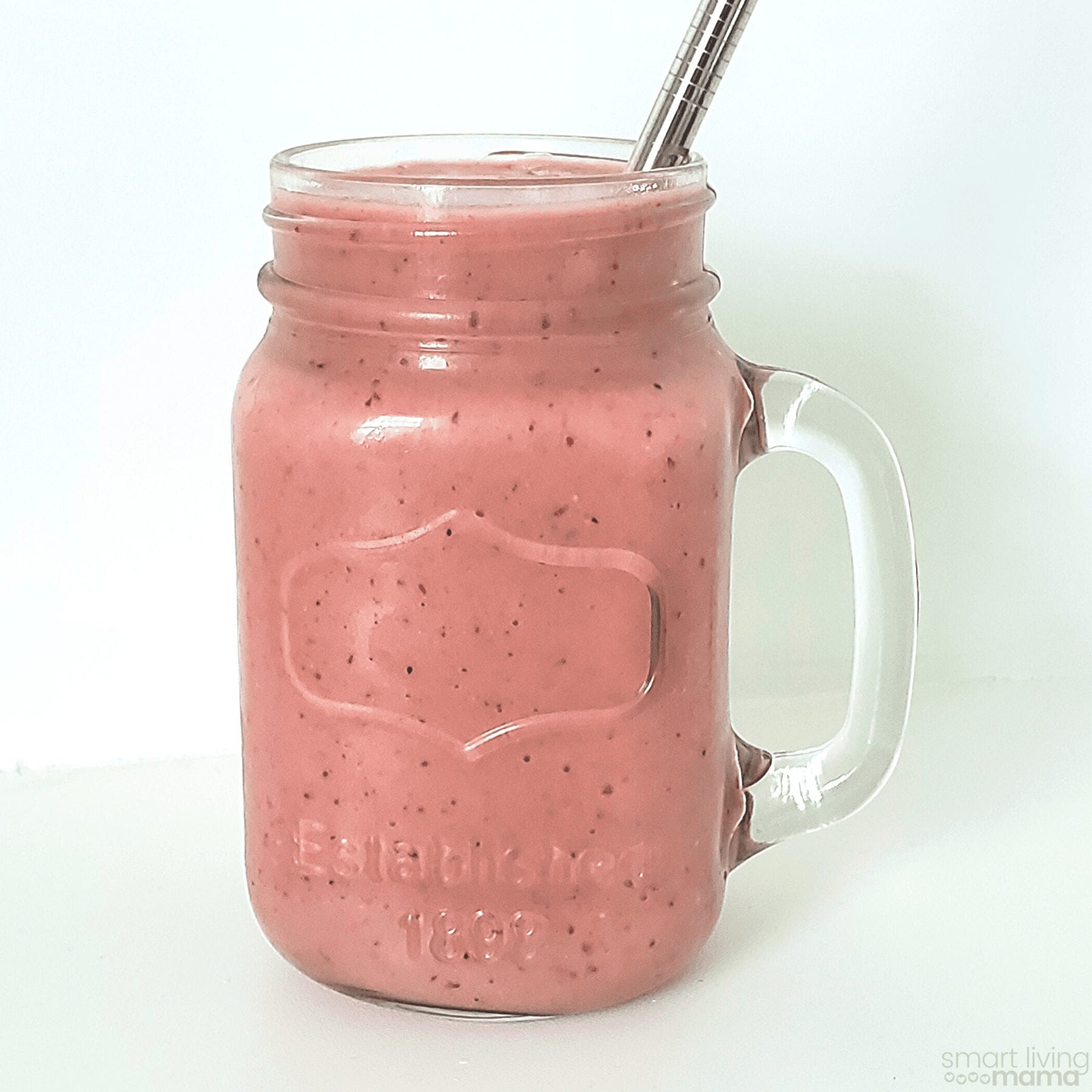 glass mason jar filled with a mixed berry smoothie and a stainless steel straw sitting in it